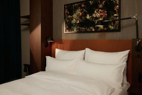 a bed with white pillows and a painting above it at The Cloud One Prague in Prague