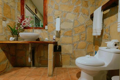 a stone bathroom with a toilet and a sink at Hotel Casa del Arbol Manuel Antonio - Adults Only in Manuel Antonio
