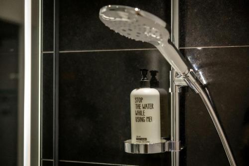 a shower head in a bathroom with a bottle of soap at The Cloud One Düsseldorf-KöBogen in Düsseldorf