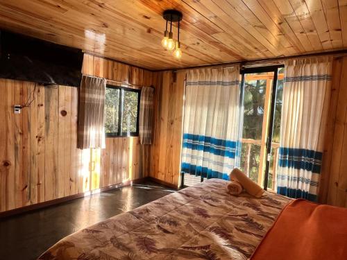 a bedroom with a bed in a room with wooden walls at Cabaña OLIN in San Mateo Río Hondo