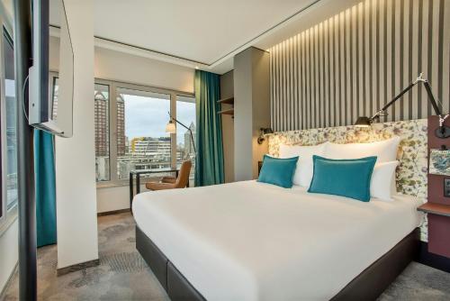 a bedroom with a large white bed with blue pillows at Motel One Rotterdam in Rotterdam