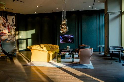 a living room with a yellow couch and chairs at Motel One Graz in Graz