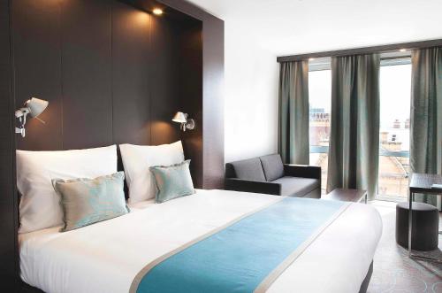 a hotel room with a large bed and a chair at Motel One Manchester-Piccadilly in Manchester