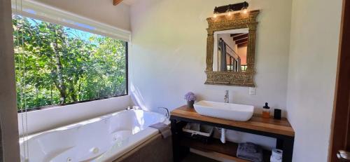 a bathroom with a tub and a sink and a mirror at Olingo Monteverde - Studio Apartment with Jacuzzi in Monteverde Costa Rica