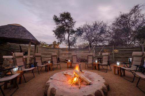 a fire pit with chairs and tables in a yard at Baluleni Safari Lodge in Grietjie Nature Reserve