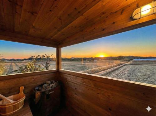 a room with a window with a view of a sunset at 絶景田園と風を感じる癒しの一棟貸しSawah東浪見 in Ichinomiya