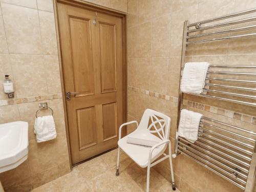 a bathroom with a chair and a sink at Long Cart Cottage in Embleton
