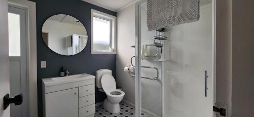 a bathroom with a toilet and a sink and a mirror at Country Harbourside Escape in Whakapirau