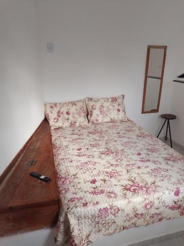 a bed with a floral bedspread and a remote control at Vila Bárbara superior in Araruama