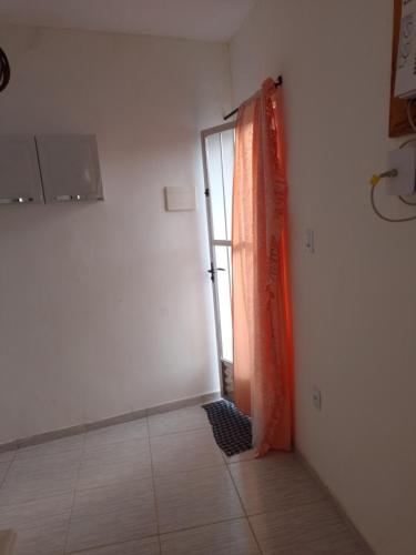 an empty room with an orange curtain and a door at Vila Bárbara superior in Araruama