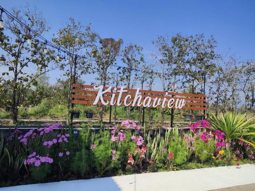a sign in the middle of a garden with flowers at Kitchaview Poolvilla พูลวิลล่า เชียงราย in Chiang Rai