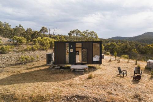 a tiny house sitting on top of a field at Bunjil by Tiny Away in Steels Creek