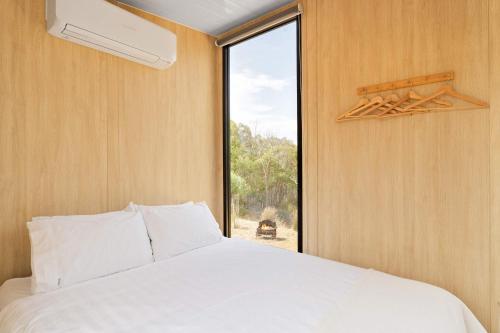 a bedroom with a white bed and a window at Bunjil by Tiny Away in Steels Creek