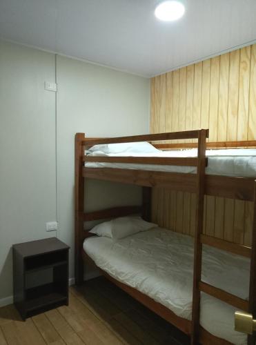 a room with two bunk beds and a night stand at Apartamentos 22 de mayo in Puerto Montt