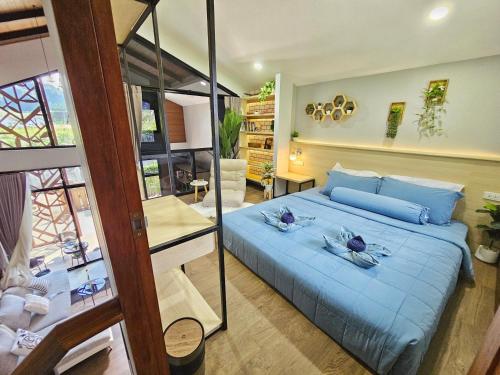 a bedroom with a large blue bed with a mirror at Ploy Mountain View Pool Villa in Ban Thai Thai