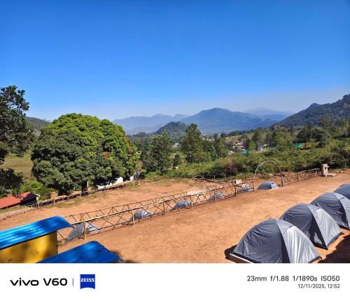 a group of tents in a field with mountains in the background at Hilltop camping vanjangi in Pāderu