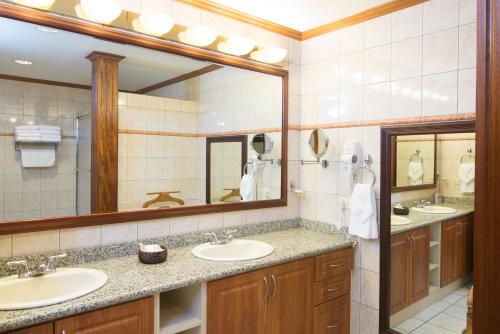 a bathroom with two sinks and a large mirror at Apartotel & Suites Villas del Rio in San José