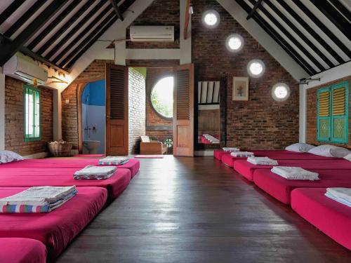 a room with a row of red beds in it at Omahe Kancaku in Balong