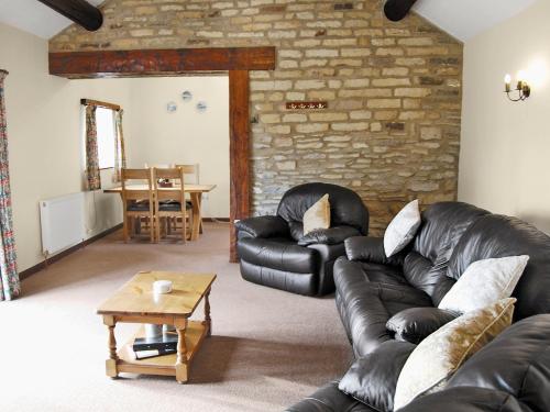 a living room with a leather couch and a table at Oak Tree Cottage in Kirkbymoorside