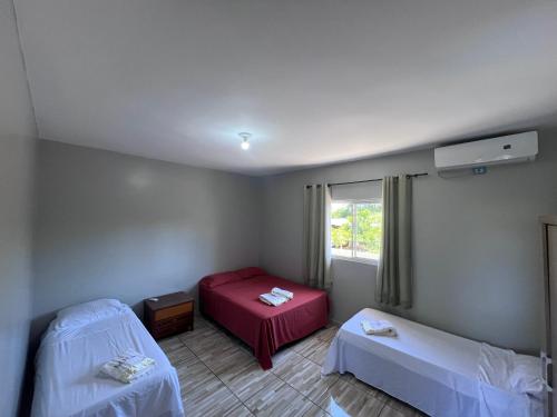 a room with two beds and a window at Chácara Tuler in Foz do Iguaçu