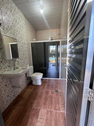 a bathroom with a toilet and a sink and a mirror at Chácara Tuler in Foz do Iguaçu