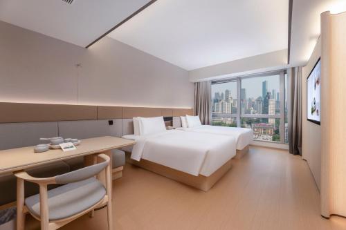 a hotel room with a bed and a desk and a window at JI Hotel Nanjing Gulou Square in Nanjing