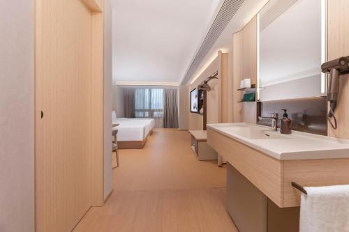 a bathroom with two sinks and a bed in a room at JI Hotel Nanjing Gulou Square in Nanjing