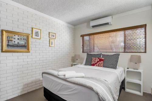 a white bedroom with a bed and a window at Anjuna, 2 bedroom apartment on canal in Mooloolaba