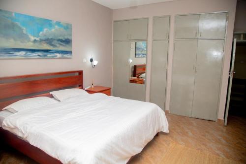 a bedroom with a white bed and a painting on the wall at Wangu Urban in Mpemba