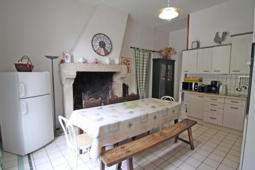 a kitchen with a table and a fireplace at Brenac in Eymoutiers
