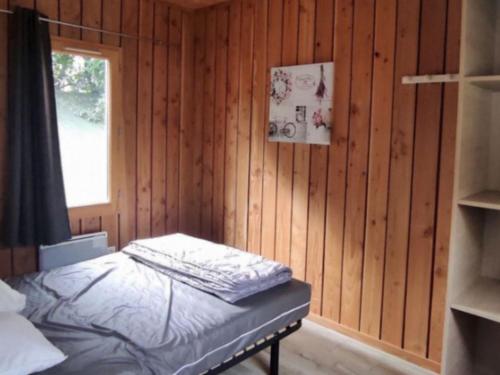 a bedroom with a bed in a wooden wall at Chalet accessible - 4 pers - Terrasse - API-1-52-1278 in Challes-les-Eaux