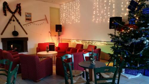 a christmas tree in a room with red chairs and a fireplace at VVF Jura Lac de Vouglans in Maisod