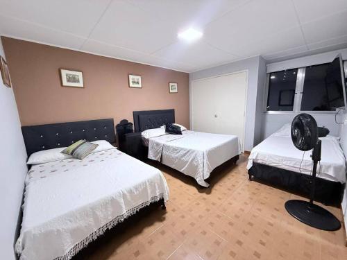 a bedroom with two beds and a fan in it at Casa hotel la 33 in Medellín