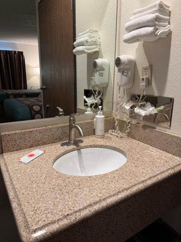 a bathroom counter with a sink in front of a mirror at Super 8 by Wyndham Selma/Fresno Area in Selma