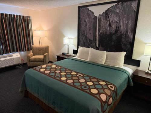 a hotel room with a large bed and a chair at Super 8 by Wyndham Selma/Fresno Area in Selma