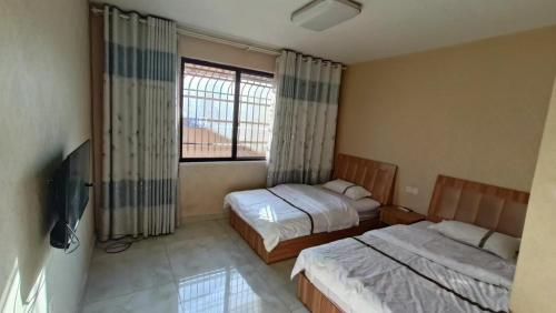 a bedroom with two beds and a tv and a window at 春栖客栈 in Chuanxingpu