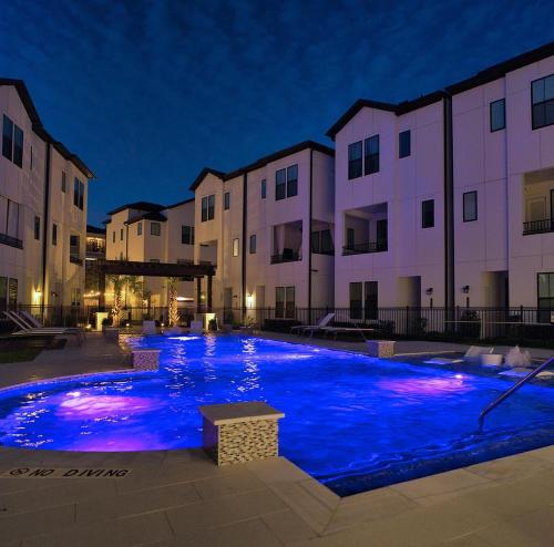 a large blue pool in front of buildings at night at The Houston Reston in Houston