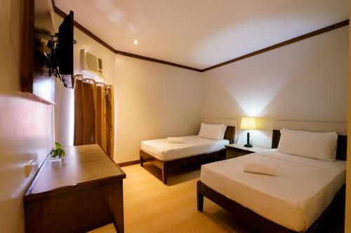 a room with two beds and a table and a desk at Madonna Hometel and Suites in Panabo