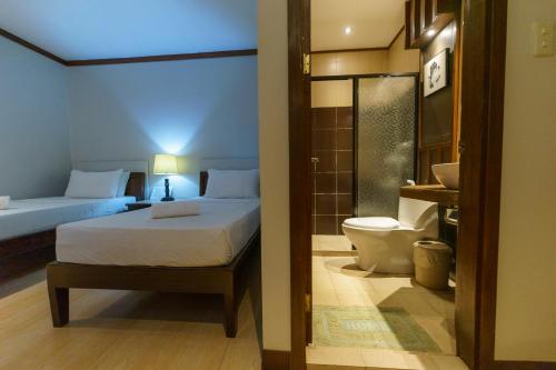 a bedroom with a bed and a toilet in a room at Madonna Hometel and Suites in Panabo