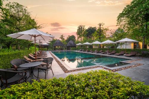 a pool at a resort with chairs and tables and umbrellas at Aravinda Resort Ninh Binh in Ninh Binh