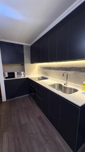 a kitchen with black cabinets and a sink at Condo luminity exclusivo 2D-2B incluye piscina parking y wifi gratis check in y seguridad 24 hrs in Los Ángeles