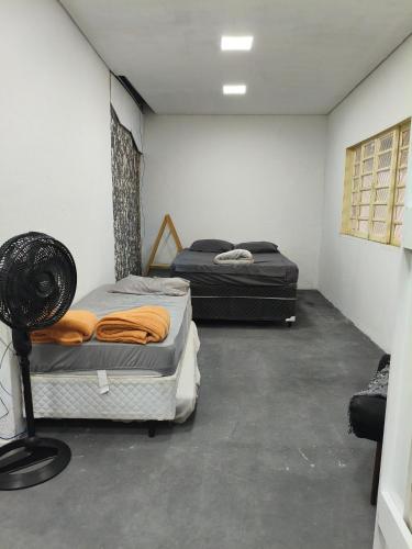 a room with two beds and a fan in it at CASA Aconchegante MASSUDA in São Paulo