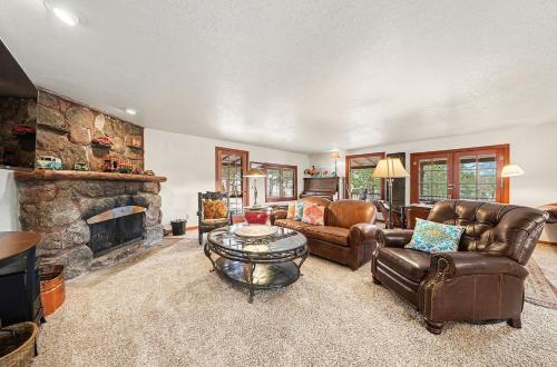 a living room with leather furniture and a stone fireplace at Twin Fawns - EV #3417 in Estes Park