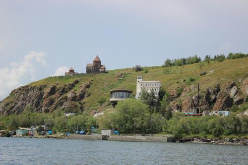 a building on a hill next to a body of water at Sevan Writers House in Sevan