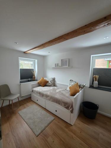 a white bedroom with a bed and two windows at Unter den Balken - mit Ofen & Ruhe Keine Monteure! in Nörten-Hardenberg