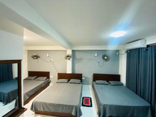 two beds in a room with blue curtains at Sensitha Holiday home in Anuradhapura