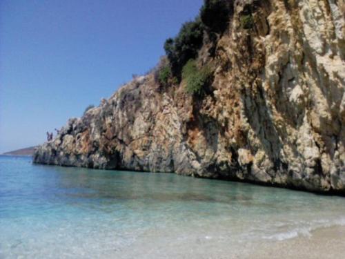 a rock cliff sticking out of the water next to the ocean at Sevilia Rooms in Qeparo