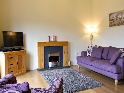 a living room with a purple couch and a fireplace at Lavender Lea in Landford