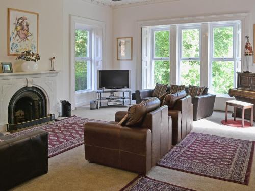 a living room with leather couches and a fireplace at Holly Lodge in Gilcrux