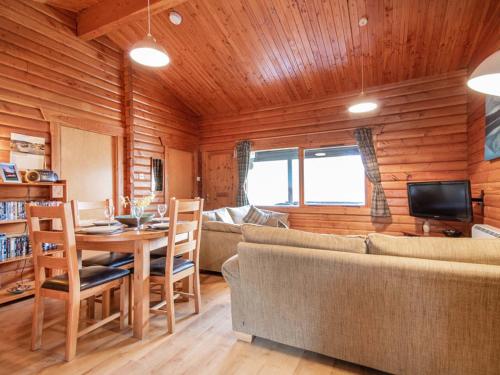 a living room with a couch and a table and chairs at Lochside Log Cabin in Brora